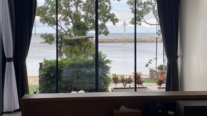 Ein Zimmer mit großem Fenster mit Blick auf ein Gewässer, einen Steg und einen Leuchtturm.