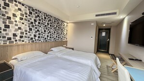A hotel room with two beds, a TV, a desk, and a wall with a geometric pattern. - Jinhwa Hotel (Keelung)