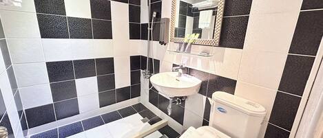 A bathroom with black and white tiles, a white sink, a toilet, and a shower.