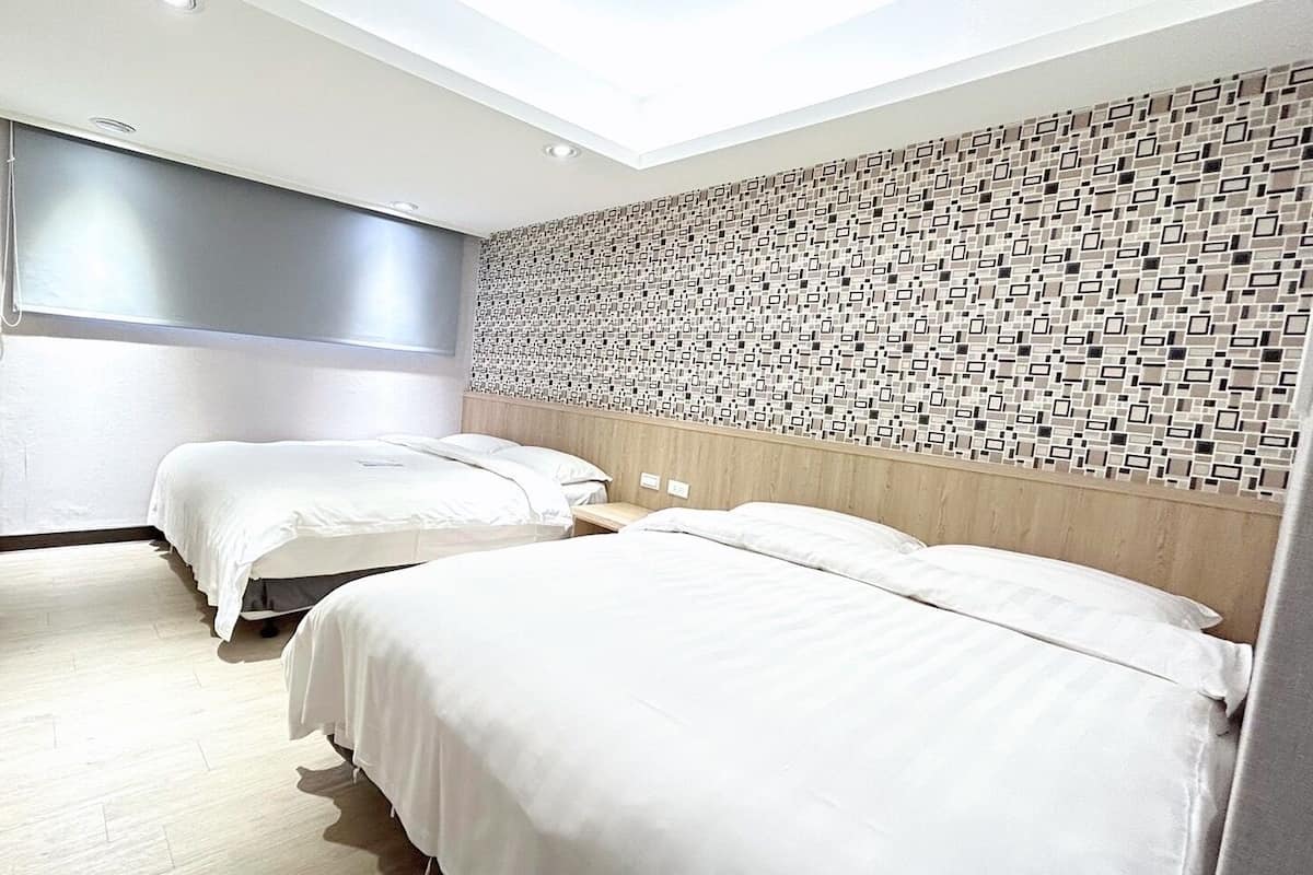A modern hotel room with two beds, a wooden desk, a shower, and a patterned wall.