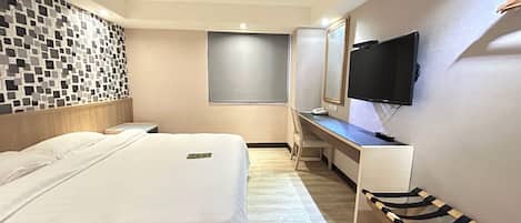 Habitación de hotel con cama, escritorio, silla, televisor y una pared con diseño tipo mosaico.