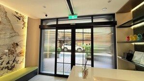 A hotel reception area with a large glass door, a marble wall, and a reception desk. - Jinhwa Hotel (Keelung)