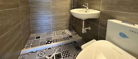 Un baño con ducha, lavamanos e inodoro.