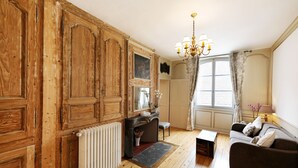 A room with wooden paneling, a radiator, a sofa, a small table, and a chandelier. - Completely renovated studio for 4, downtown Salins Les Bains with garden (Salins-les-Bains)