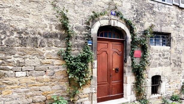 A stone building with a wooden double door, a small window, and a sign above the door. - Completely renovated studio for 4, downtown Salins Les Bains with garden (Salins-les-Bains)