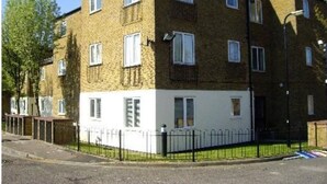 A multi-story residential building with a brick facade, white lower section, and a black metal fence surrounding the property. - 2 bedroom Apartment  Heathrow Airport (Hayes)