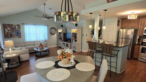 A spacious living area with a dining table, sofas, and a kitchen in the background. - Reviews, Location, Amenities, Owner Managed. That's why. Book it. (Foley)