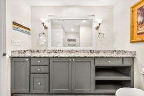 A bathroom with a marble countertop, a large mirror, and a towel rack.