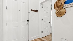 A hallway with white double doors, a coat rack with hats, and a wall-mounted sign.