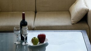 Ein Balkon mit einer Couch, einem Tisch mit einer Weinflasche, zwei Gläsern und einem Teller mit einem Apfel und einer roten Frucht.