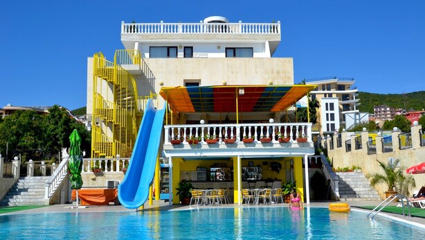 Ein Hotel mit Schwimmbad, einer blauen Rutsche und Außenbereich mit Sitzgelegenheiten.
