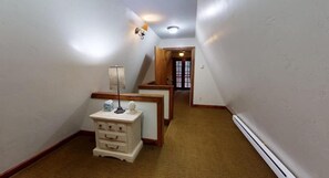 Passadís estret amb una banca de fusta, un lamp i una porta al final.
