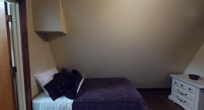 Ein Schlafzimmer mit Bett, Kommode und Tür.