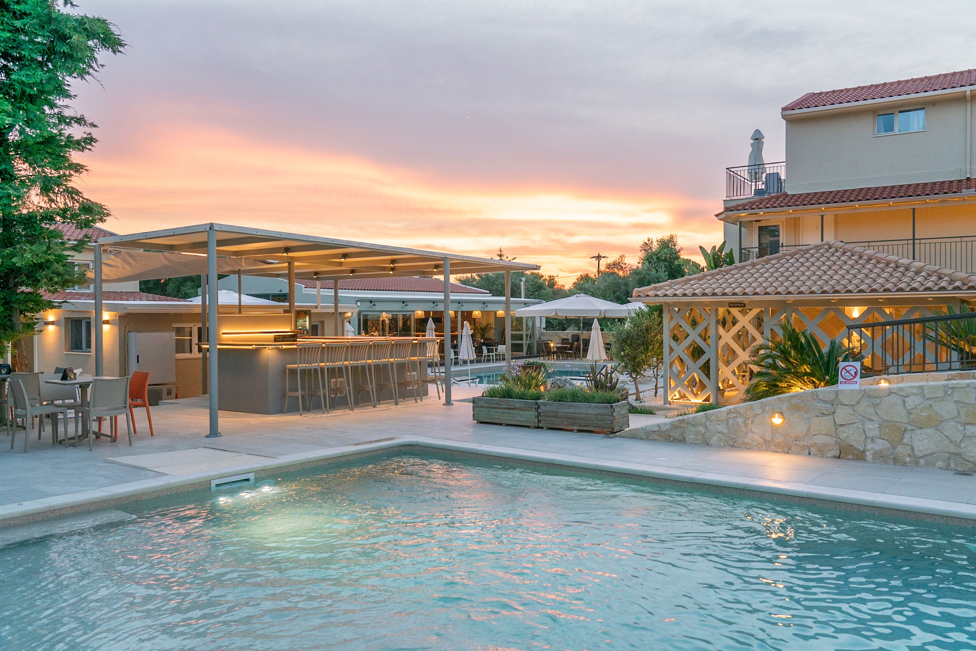 Una piscina con un patio techado, zona de estar exterior y un bar.