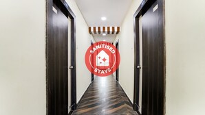 A hallway with dark wooden doors, a polished floor, and a sign indicating the area is sanitized. - OYO 63209 Hotel Ram Ratan Grand (Hyderabad)