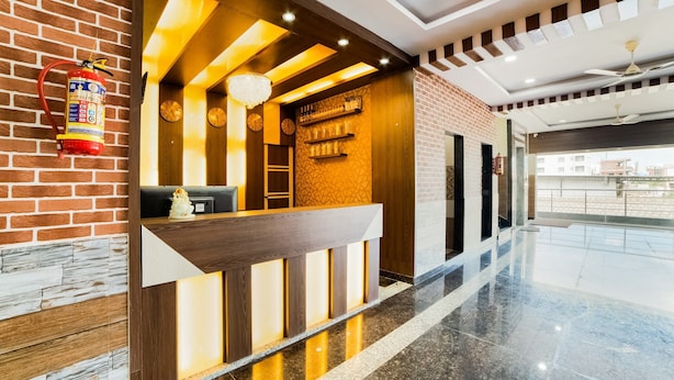 A reception area with a wooden reception desk, a fire extinguisher mounted on the wall, and a clock. - OYO 63209 Hotel Ram Ratan Grand (Hyderabad)