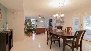 Ein Essbereich mit Holztisch und -stühlen, einer Chandelierleuchtre und einem Deckenventilator.