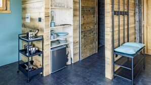A rustic kitchen with wooden beams, a black metal shelf, and a sliding door.