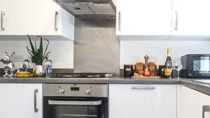 A modern kitchen with stainless steel appliances, including an oven and a microwave. - Tudors eSuites Birmingham House Private Garden Free Parking (Birmingham)
