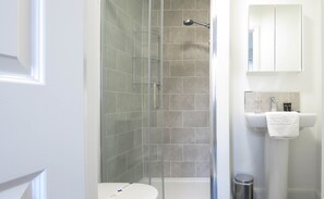 A modern bathroom with a glass-enclosed shower, a white sink, and a mirror above it. - Tudors eSuites Birmingham House with Private Garden Free Parking (Birmingham)