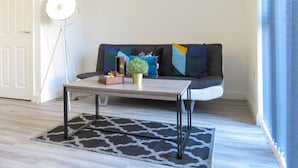 Un salon moderne avec un canapé, une table basse, une plante en pot et une lampe.
