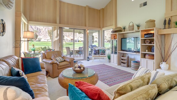 A spacious living area with a leather sofa, a round coffee table, and a TV on a stand. - PGA West Mtn Course: Luxury Golf Retreat! (La Quinta)