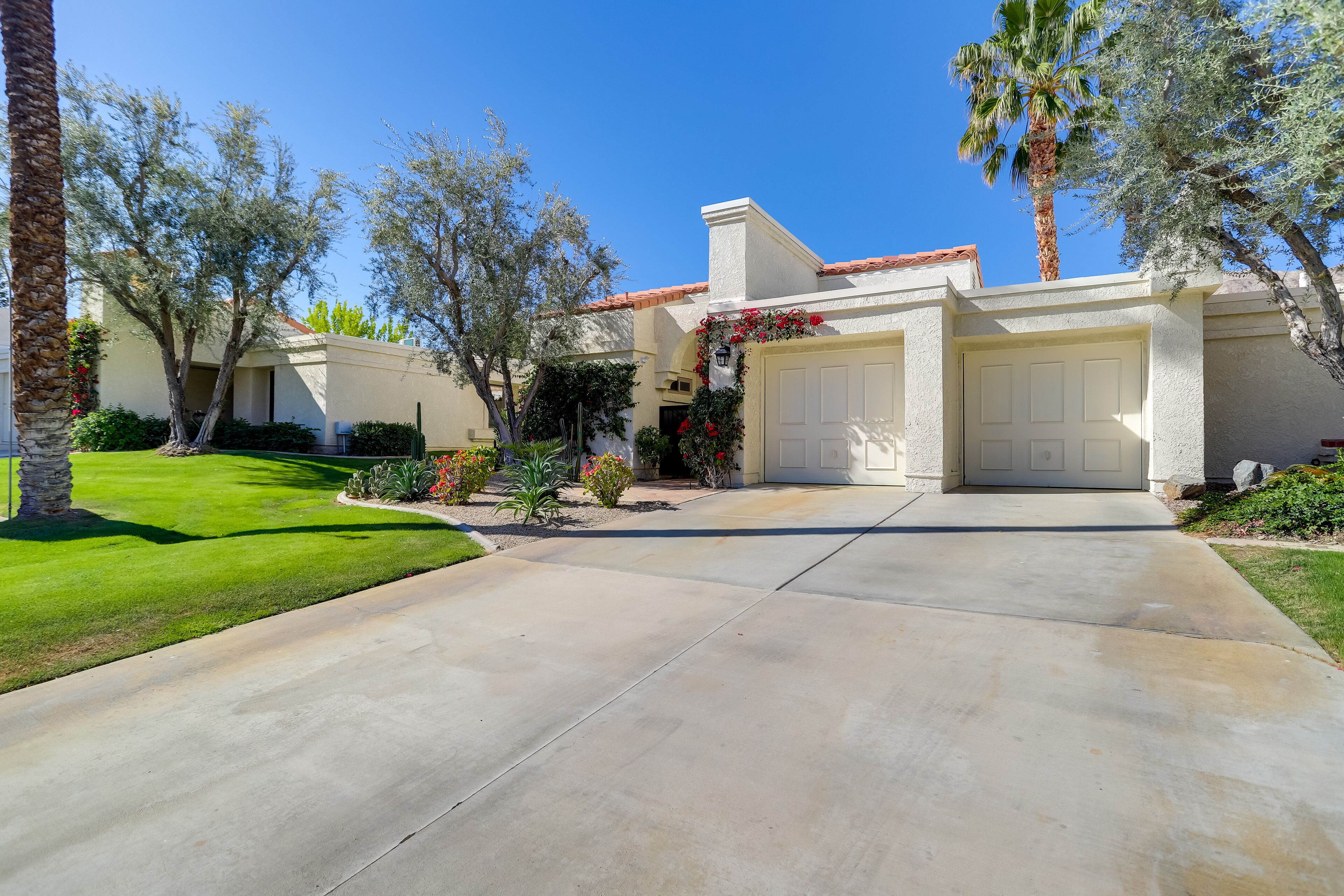 A residential house with a front driveway, two garage doors, and a well-maintained lawn.