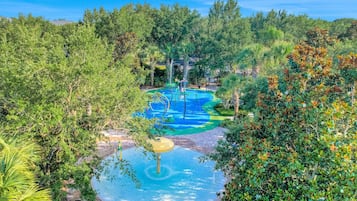 Escape to a serene tropical oasis with a central water play area surrounded by lush foliage and trees.