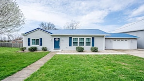 A single-story house with a blue roof and white siding, a front porch, and a garage.