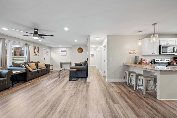 A modern living room with a sofa, coffee table, and a dining area with bar stools.