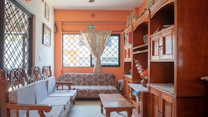 A room with a sofa, wooden tables, a cabinet, and a window with a curtain. - Capital O Hotel Aurora, Tuxtla Gutiérrez (Tuxtla Gutierrez)