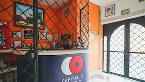 A reception area with a blue counter labeled "Capital O by OYO," a chain-link fence, and a door with a sign reading "Salida de Emergencia." - Capital O Hotel Aurora, Tuxtla Gutiérrez (Tuxtla Gutierrez)