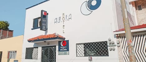 A building with a sign for "Aurora Hotel" and a red circular logo.