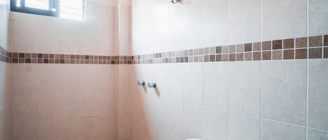 Ein Badezimmer mit Dusche, Toilette und Fenster.