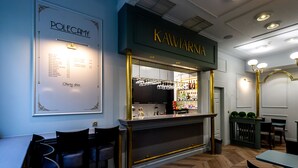 Un espace bar comprenant un tableau affichant le menu, un comptoir et des sièges.