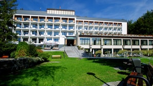 Un hôtel à plusieurs étages doté d’une entrée principale, d’un espace extérieur aménagé pour s’asseoir et d’une pelouse bien entretenue.