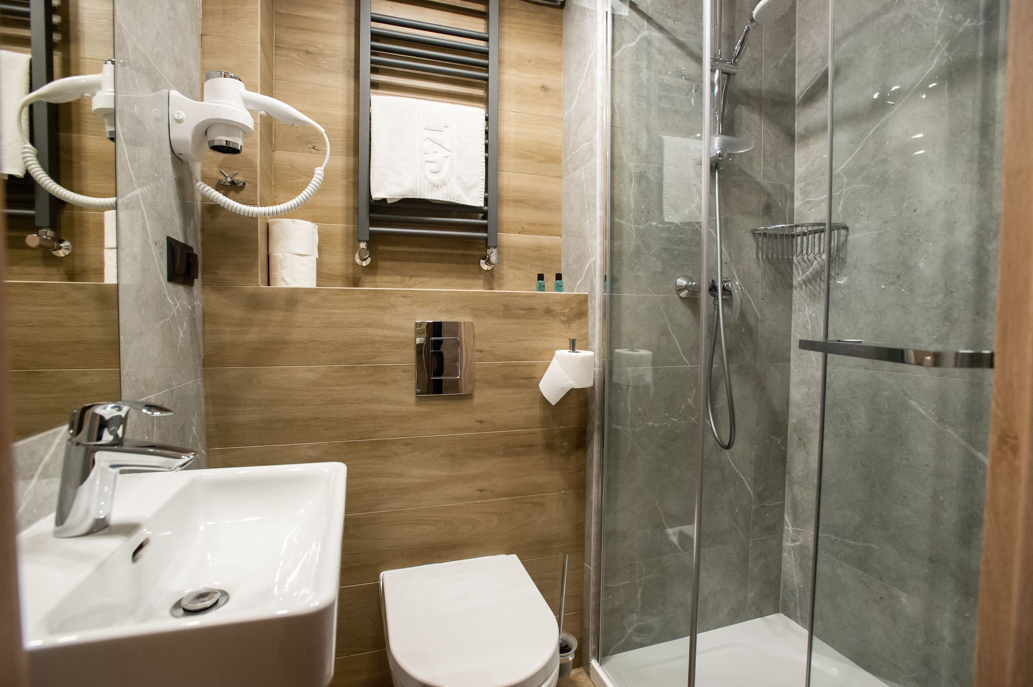 Une salle de bain moderne avec une douche à parois de verre, un lavabo blanc et des toilettes.