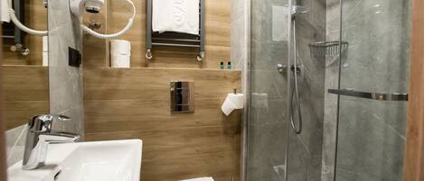 A modern bathroom with a glass-enclosed shower, a white sink, and a toilet.