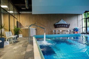 An indoor swimming pool with a water fountain, seating area, and a sign reading "ZAGRON". - Hotel Halo Szczyrk (Szczyrk)