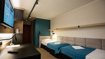 A hotel room with two beds, a desk with a TV, and a phone.