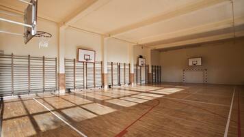 Una cancha de baloncesto cubierta con múltiples aros, suelo de madera y techos altos.