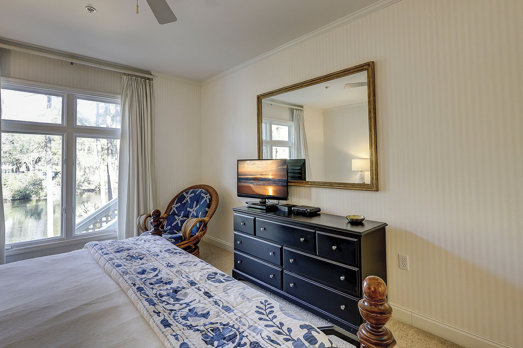 A bedroom with a bed, dresser, chair, and a large mirror.