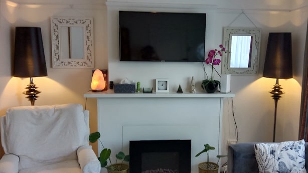 Een woonkamer met een open haard, een televisie erboven en twee lampen aan weerszijden.