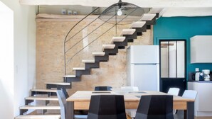 Eine moderne Küche mit integriertem Treppenhaus, einem Esstisch mit Stühlen und einem Kühlschrank.