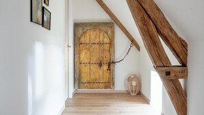 Ein Korridor mit einer rustikalen Holztür, einem gewebten Korb und Holzbalken.