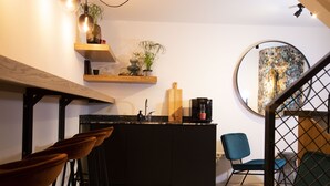 A modern kitchen with a black countertop, wooden bar stools, and a coffee machine. - Hotel Haverkist ('s-Hertogenbosch)