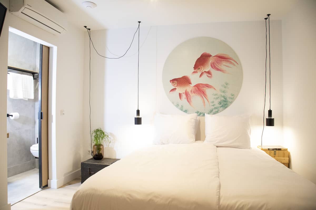 Un dormitorio con una cama grande, un cuadro de peces colgado en la pared, lámparas de noche y una mesita de noche de madera.