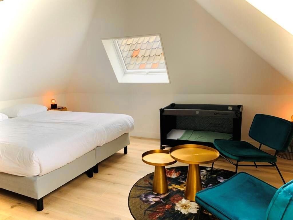 Een slaapkamer met een bed, een bureau, een stoel en een dakraam.