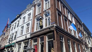 A multi-story building with a prominent clock and a statue on the facade. - Hotel Haverkist ('s-Hertogenbosch)