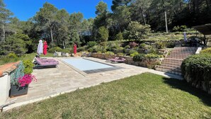A backyard with a swimming pool, lounge chairs, and a stone staircase leading to a covered area. - NICE HOUSE LOCATED IN THE HEART OF THE VAR  (Draguignan)